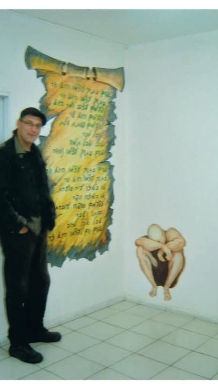A person presents a decorative scroll-shaped panel with lettering.